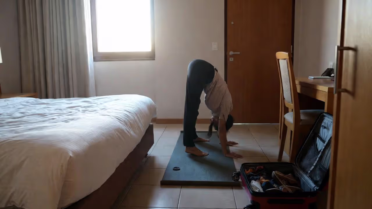 Traveler maintaining yoga practice in a small hotel room.